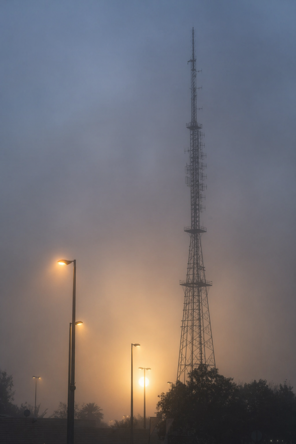 Telecom tower edited with dense morning fog and a soft sun disc